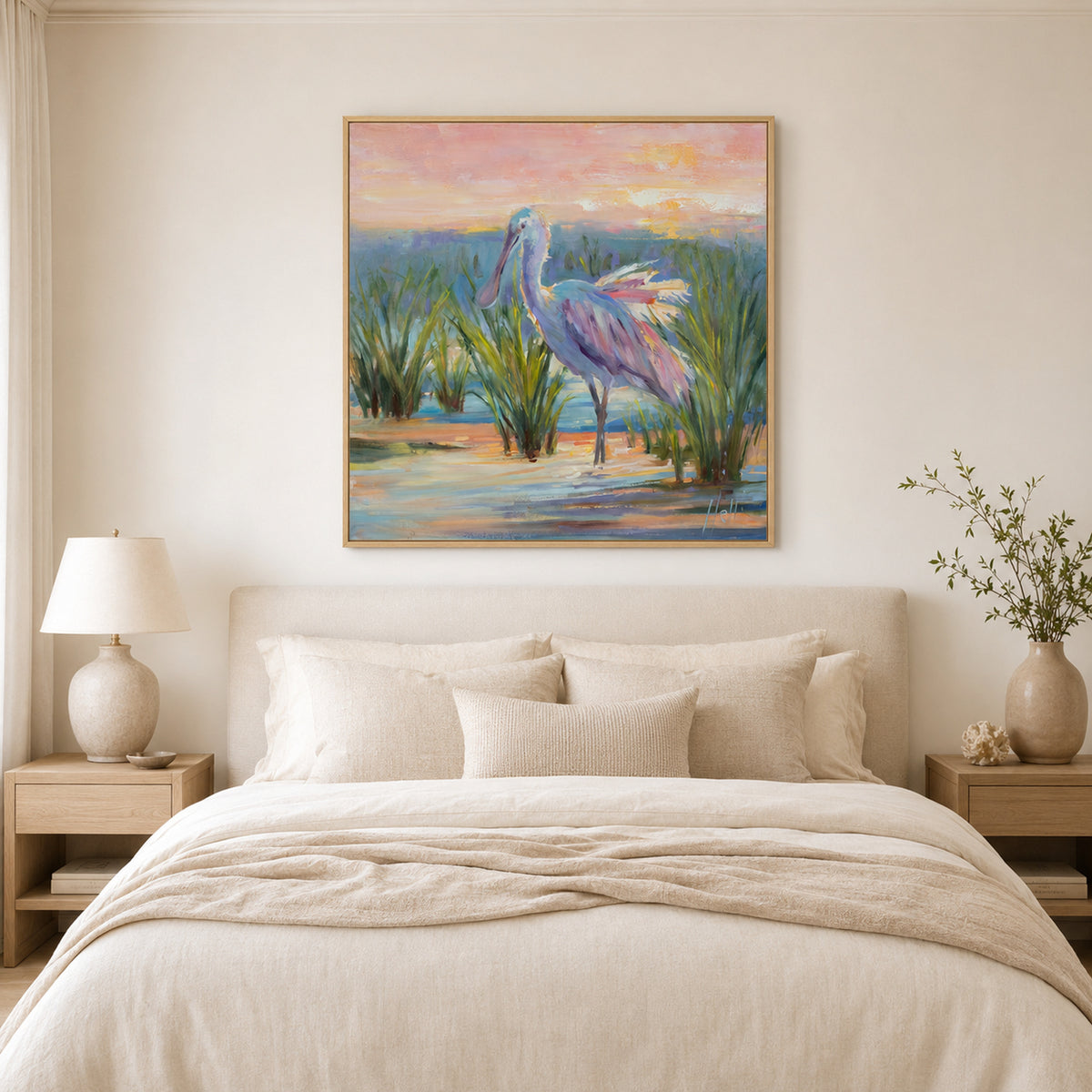 A framed painting of a pink spoonbill standing in marsh grass at sunset, displayed on a beige wall above a neatly made bed in a softly styled bedroom.