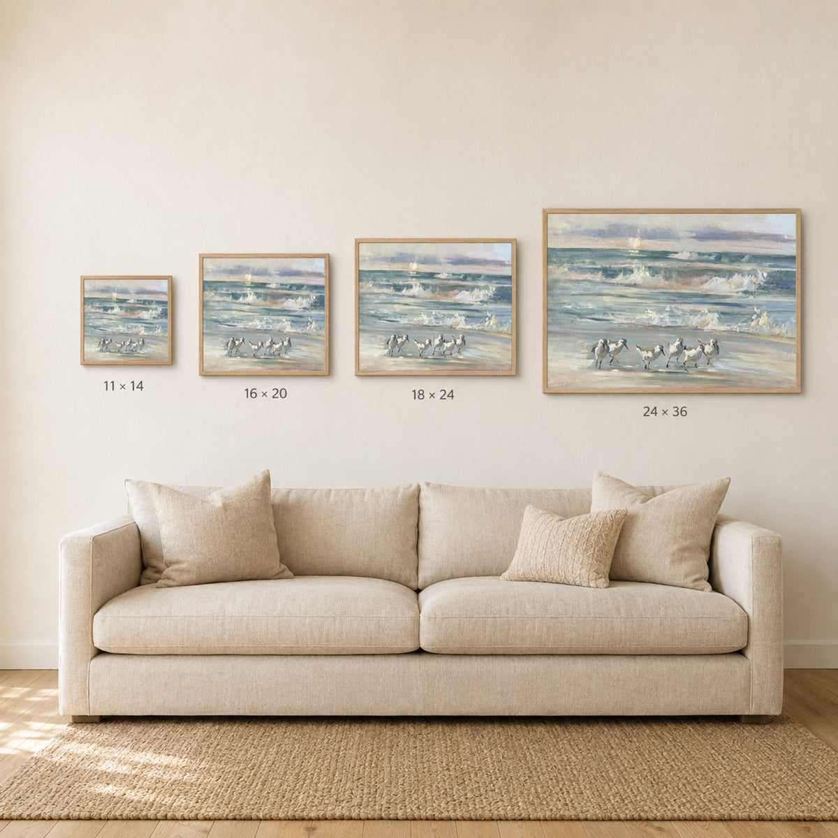 A staged living room scene showing a beige sofa beneath four framed ocean paintings of increasing size, with size labels printed below each frame. Because a real interior environment is present, this fits Lifestyle rather than Product/Packaging.
