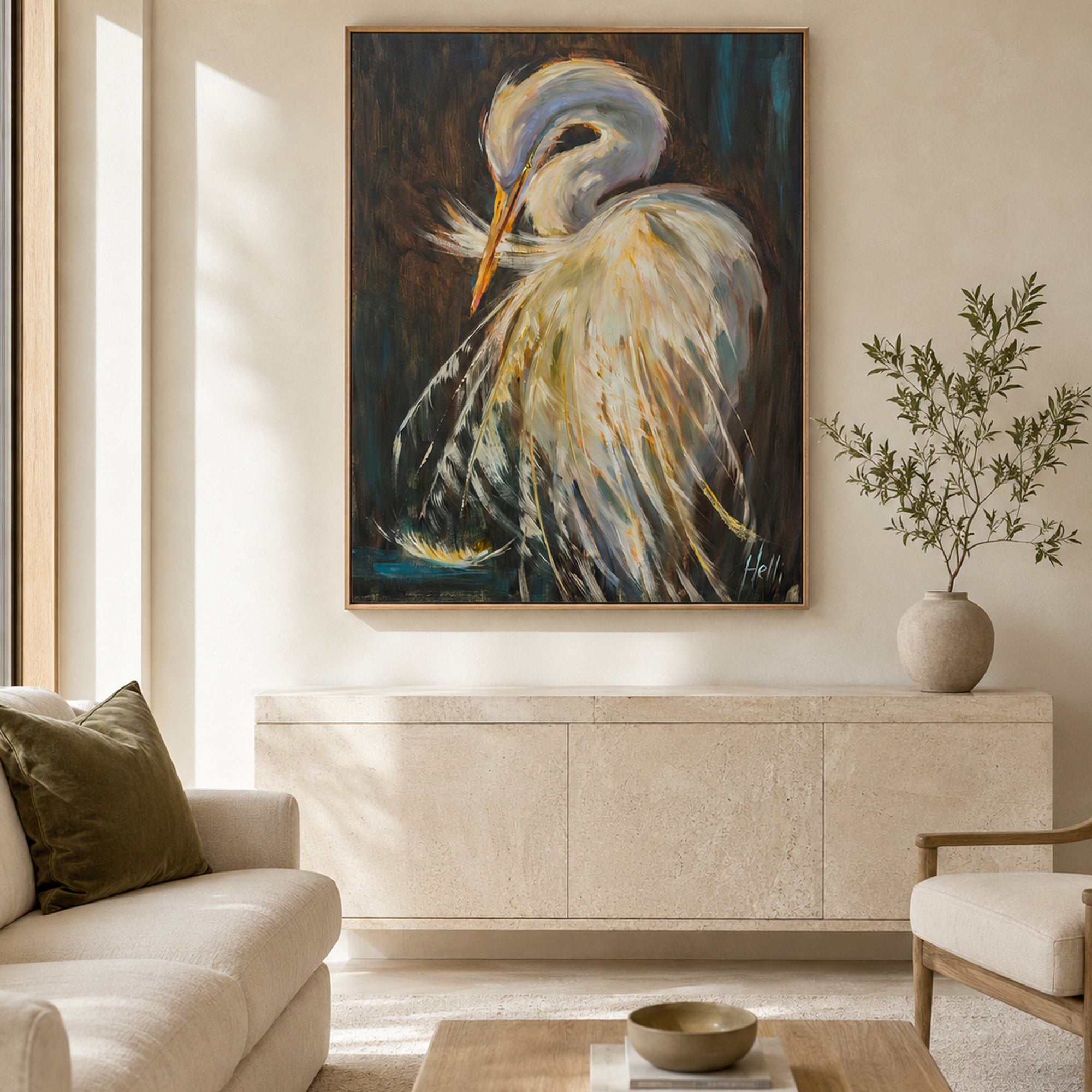 A framed canvas painting of a white heron with blue, yellow, and orange accents, displayed on a beige wall in a modern living room setting above a stone console table.