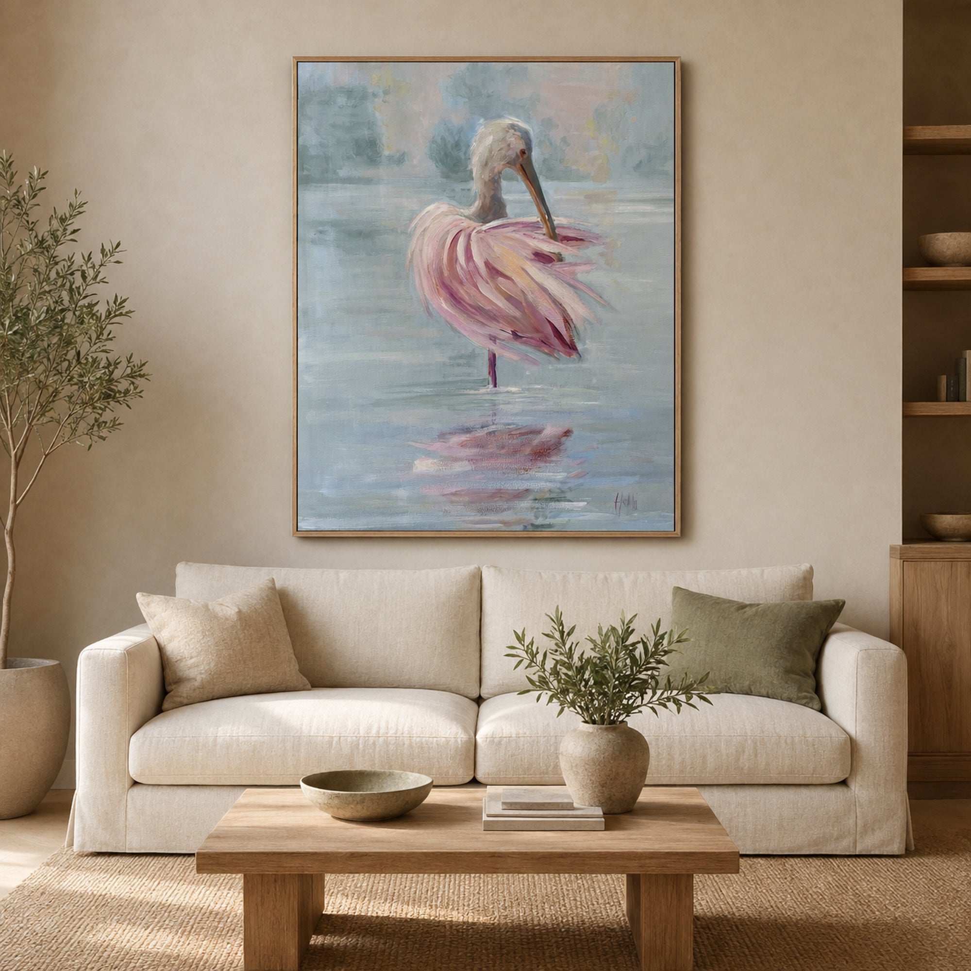 A framed vertical canvas painting of a pink spoonbill standing in water, displayed on a beige wall above a cream-colored sofa in a modern living room setting.