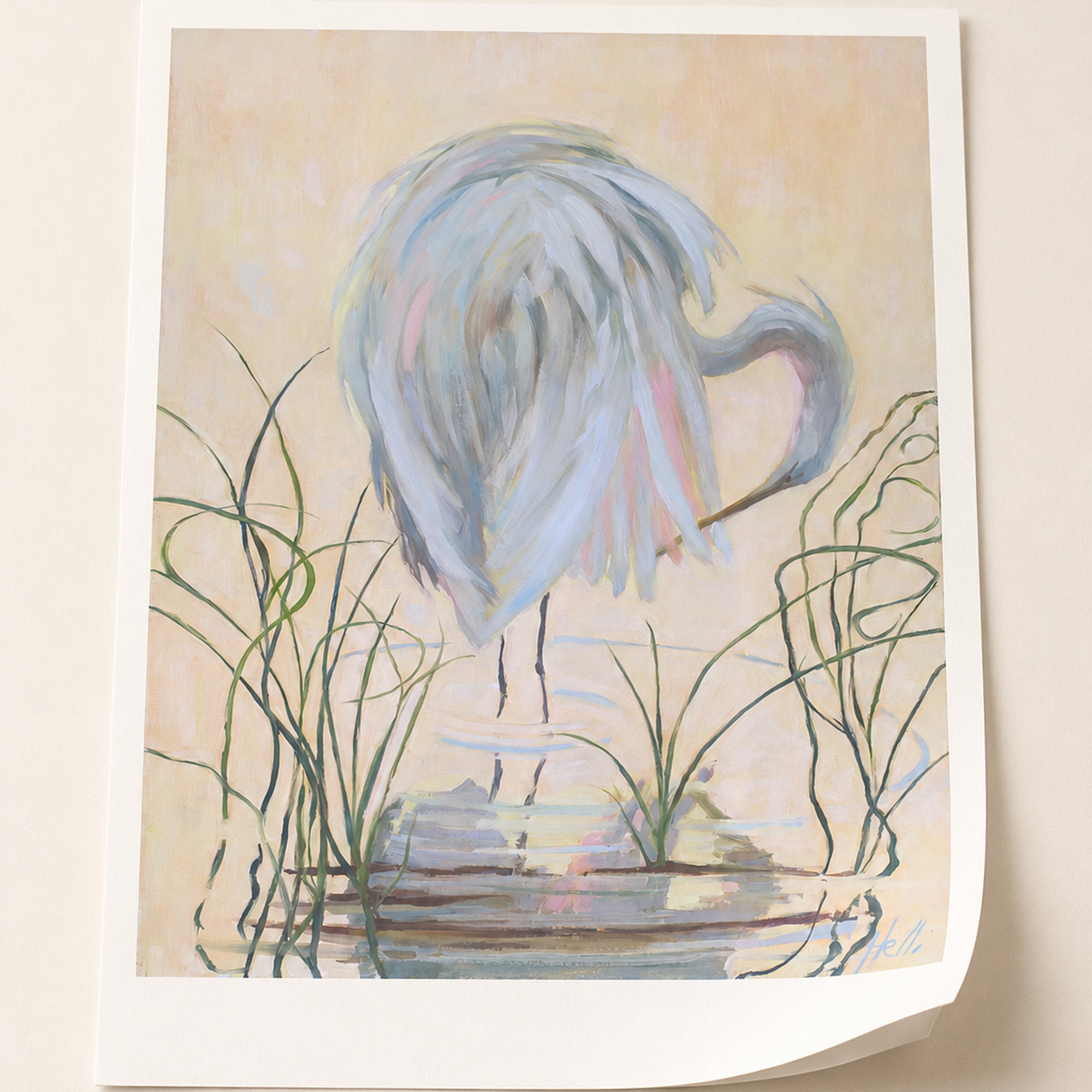 A square art print featuring an impressionistic painting of a pale blue heron standing in shallow water with reeds, shown against a light beige background.