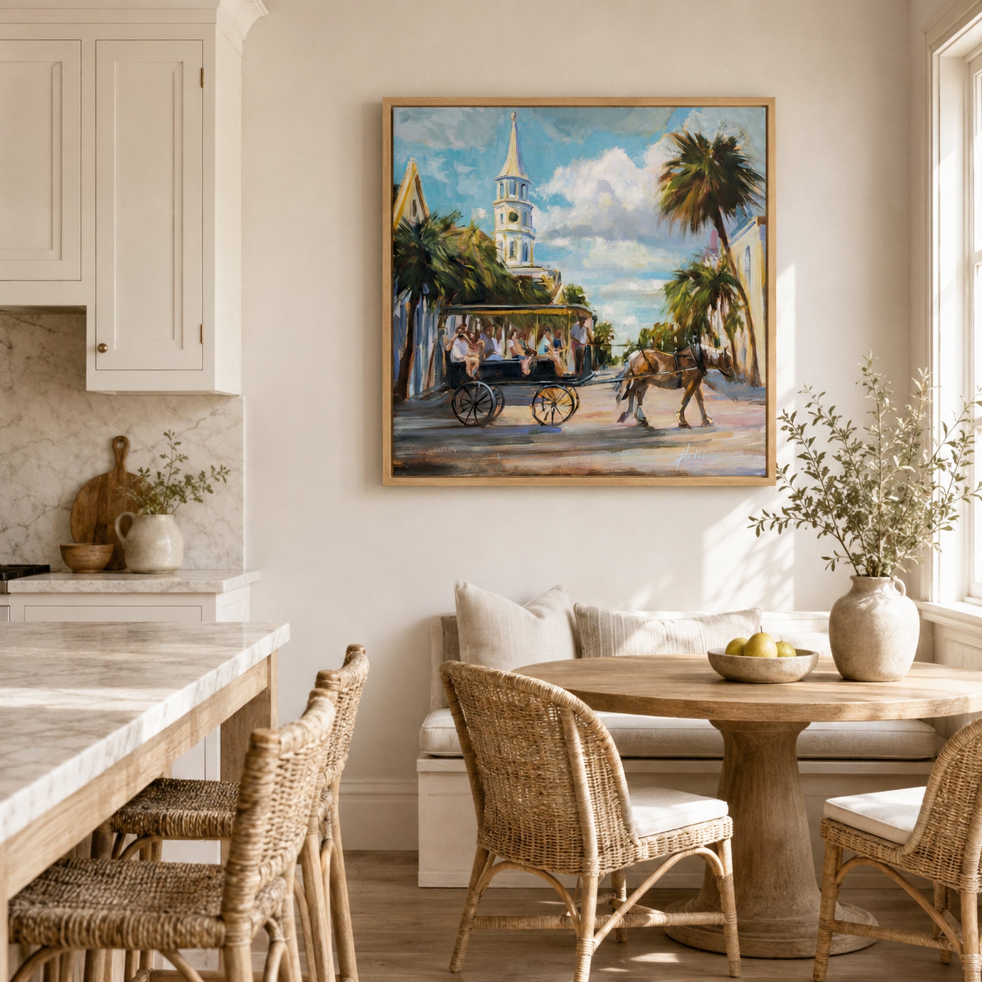 A framed painting of a historic street scene with a church steeple, horse-drawn carriage, and palm trees, displayed on a beige wall in a bright, modern kitchen and dining room setting.