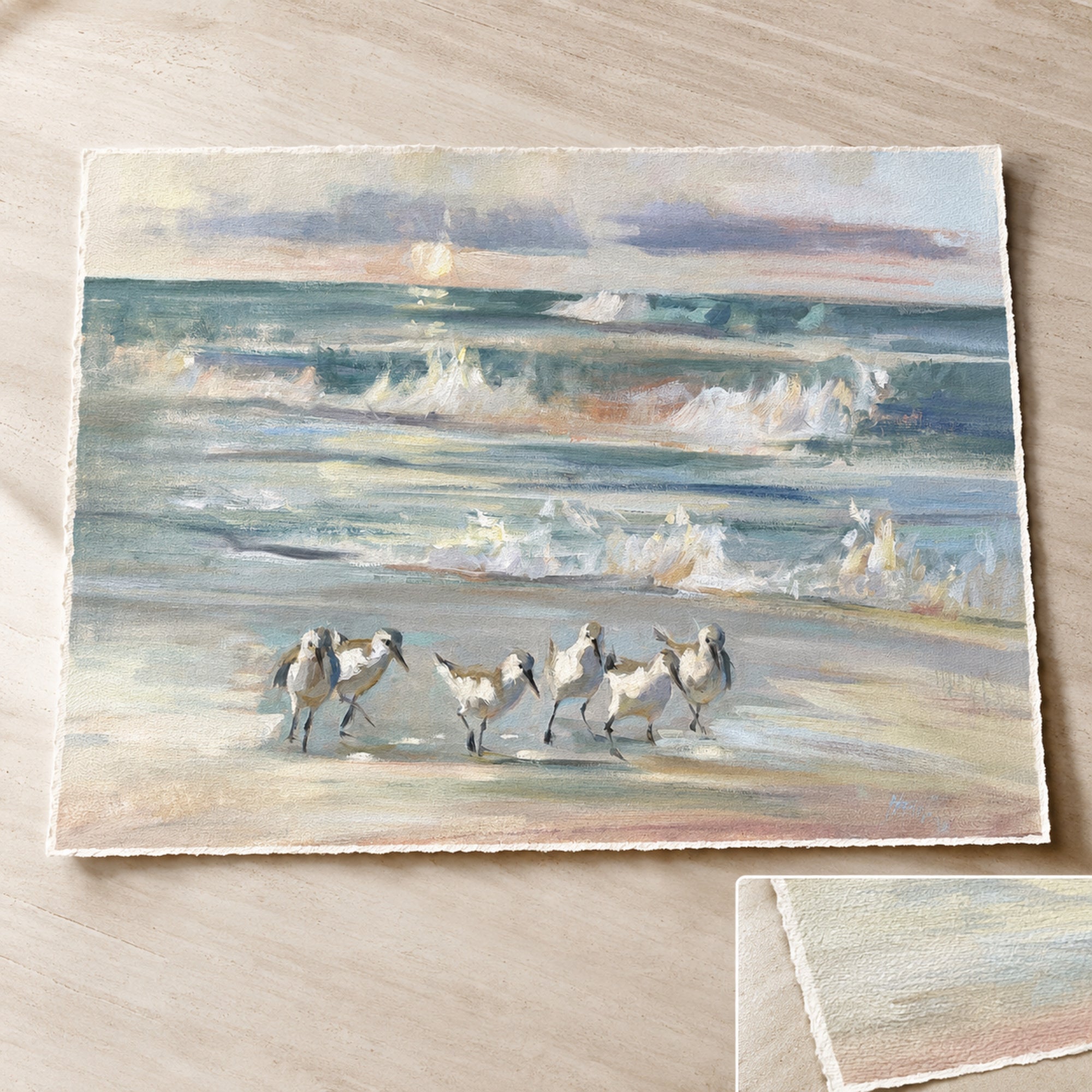 A square watercolor painting of Sandpipers walking on a sandy beach with ocean waves in the background, displayed on a light wood surface.