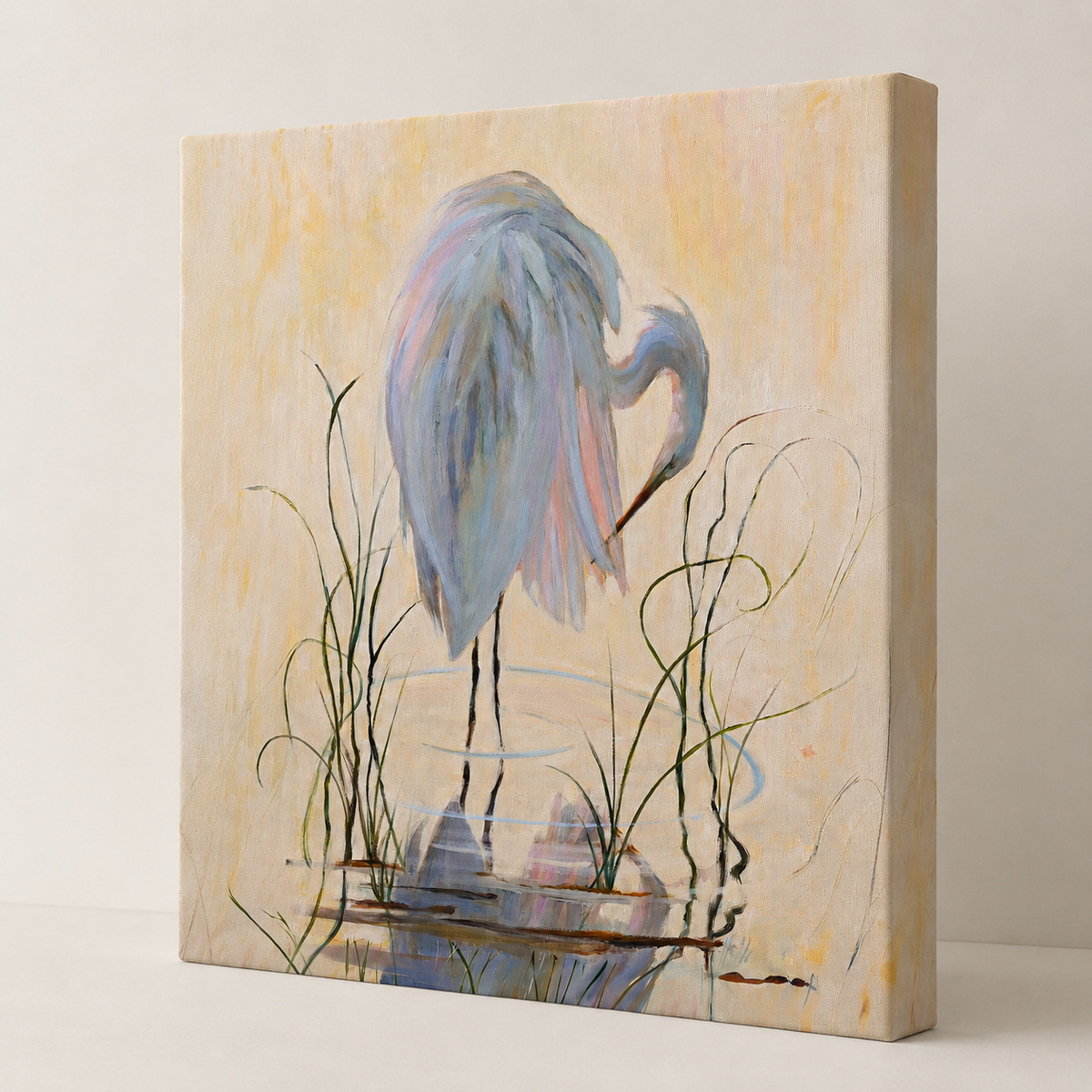 A square canvas wall art print featuring a painted heron standing in shallow water with reeds, shown at a slight angle against a plain light background.